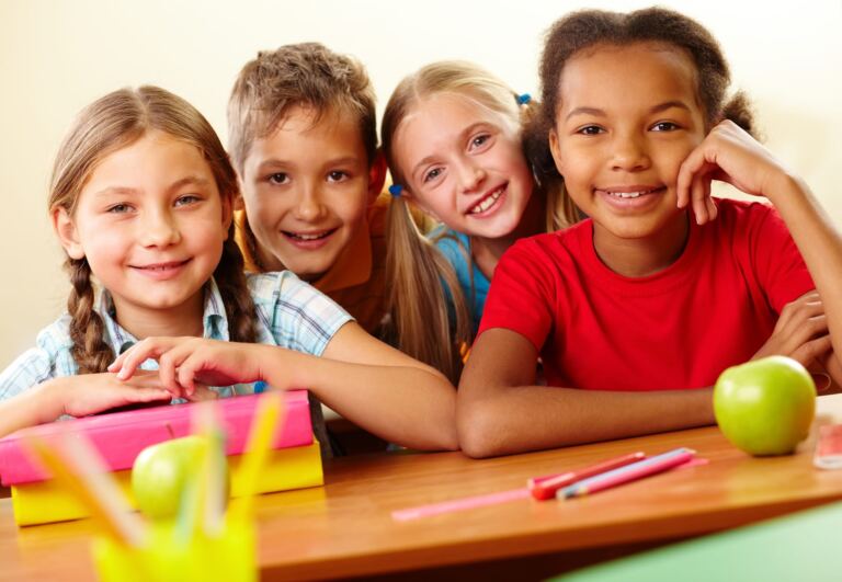 Portrait of smart schoolchildren looking at camera in classroom